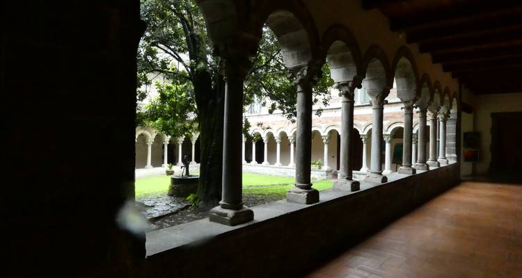 Stenen klooster met gewelfde zuilen die een rustige binnentuin omlijsten.