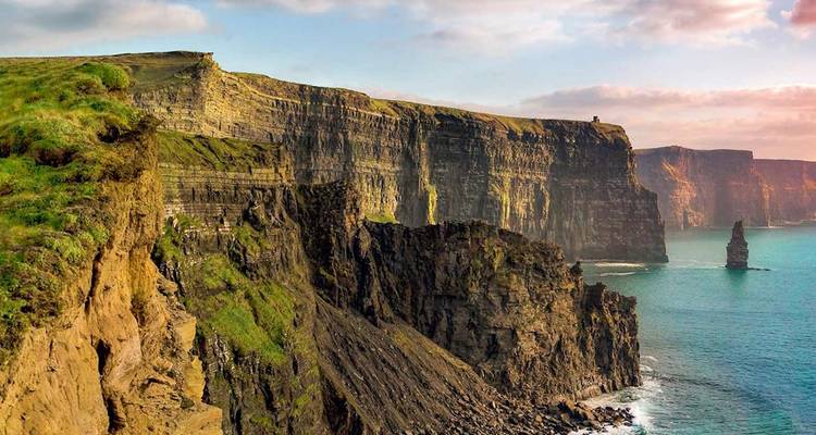 Acantilados marinos dramáticos se precipitan hacia aguas turquesas en los famosos Acantilados de Moher bajo un cielo pastel.