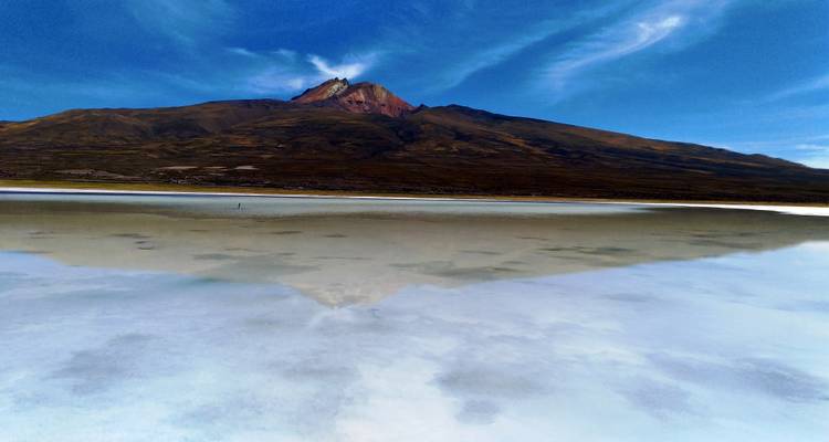 Un lago que refleja montañas bajo un cielo azul despejado.