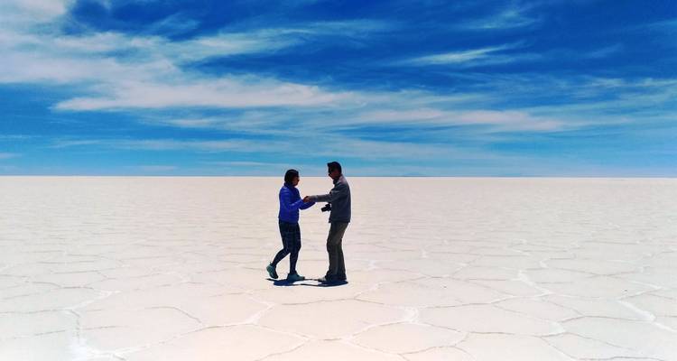Dos personas tomadas de la mano en medio de un salar.