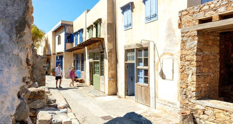 Calle de piedra bañada por el sol con casas restauradas en la isla de Spinalonga.