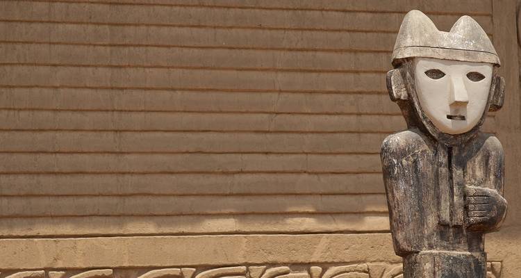 Kulturskulptur vor einer alten Lehmziegelmauer.