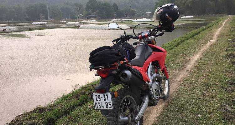 Moto garée près d'un sentier rural le long de l'eau.