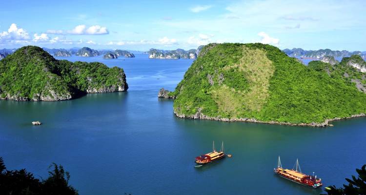Panoramisch uitzicht op een baai met kalkstenen eilanden en traditionele boten.