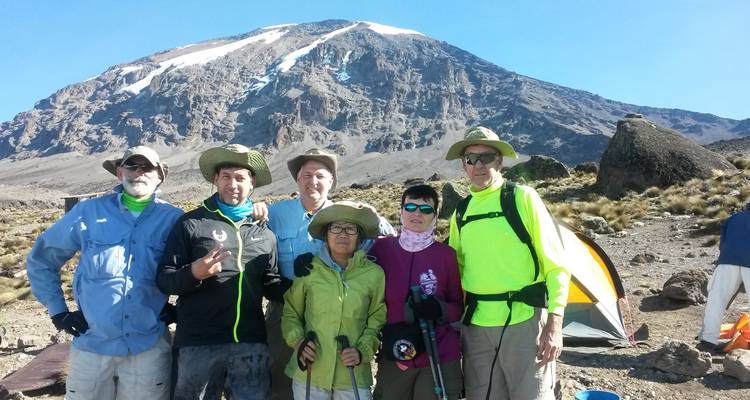 Un groupe de randonneurs posant devant une montagne.