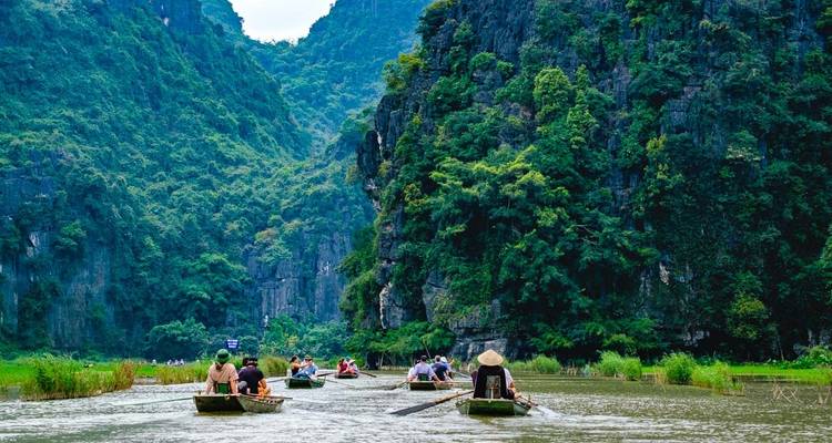 Tourists in boats navigating through a lush river valley