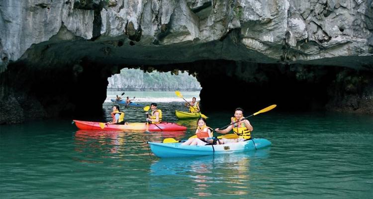People kayaking in a cave with clear green water