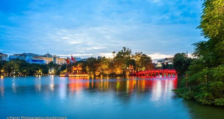 Sunset view of a city with a bridge outlined by colorful lights