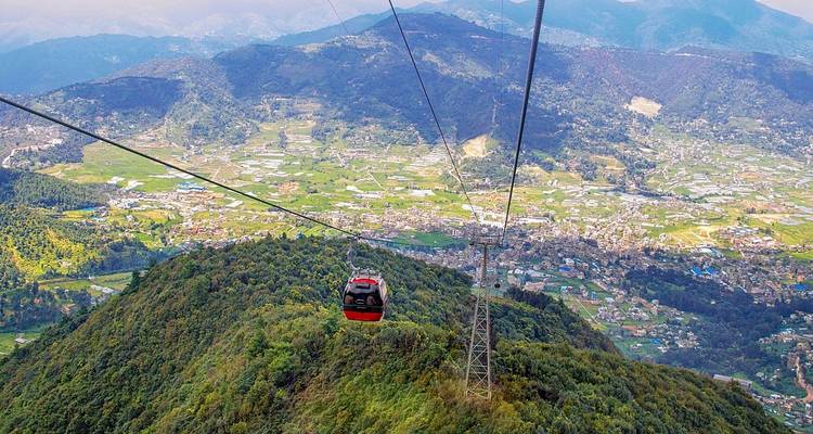 Cable car over green hills and a distant cityscape.
