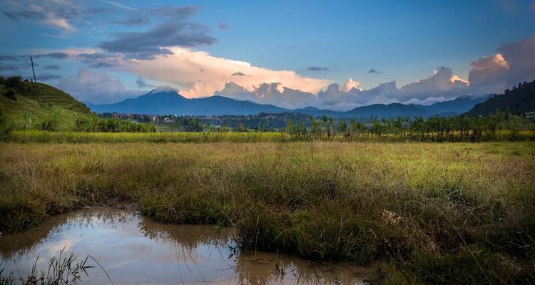 Expansive landscape with a small pond and distant mountains.