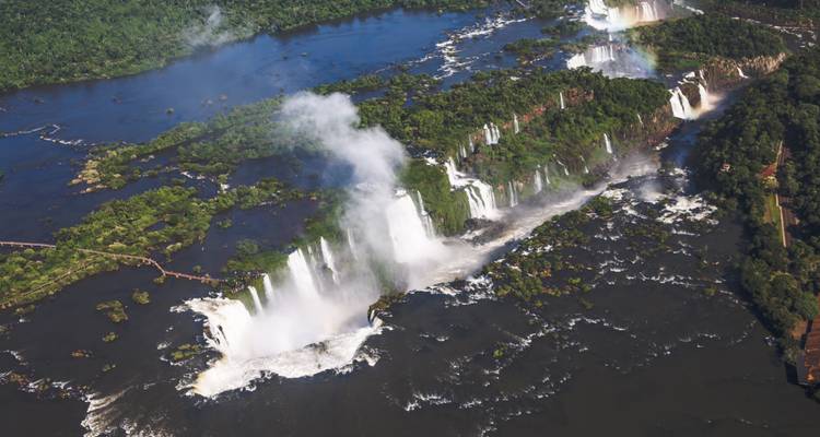 Aerial view of Iguazu Falls with water cascading down multiple waterfalls.