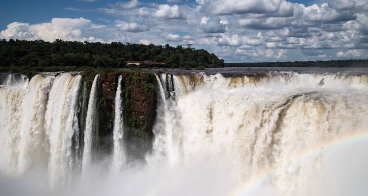 Close-up of the powerful water flow at Iguazu Falls with a visible rainbow.