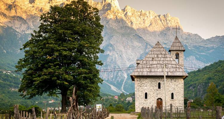 Une église saisissante sur fond de montagne avec la lumière du soir.