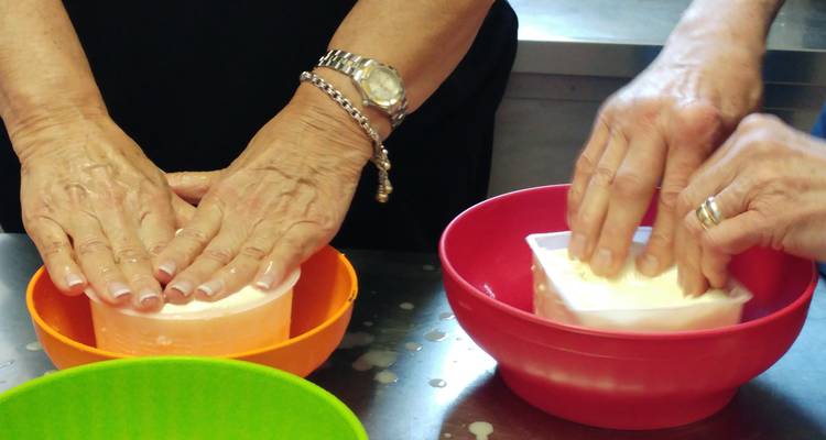 Primer plano de manos presionando queso en moldes.