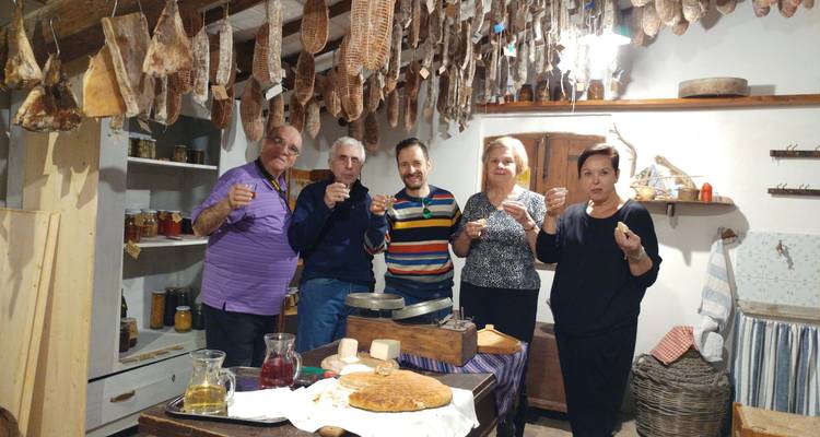 Grupo de personas en una habitación rústica y acogedora con embutidos colgando.