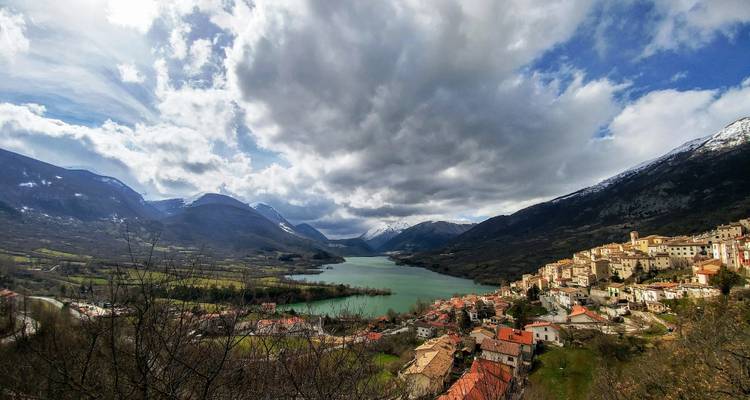 Vista panorámica de un lago rodeado de montañas y un pueblo en la ladera.