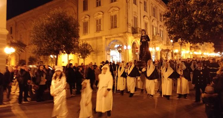 Procesión religiosa con personas vestidas con trajes tradicionales por la noche.