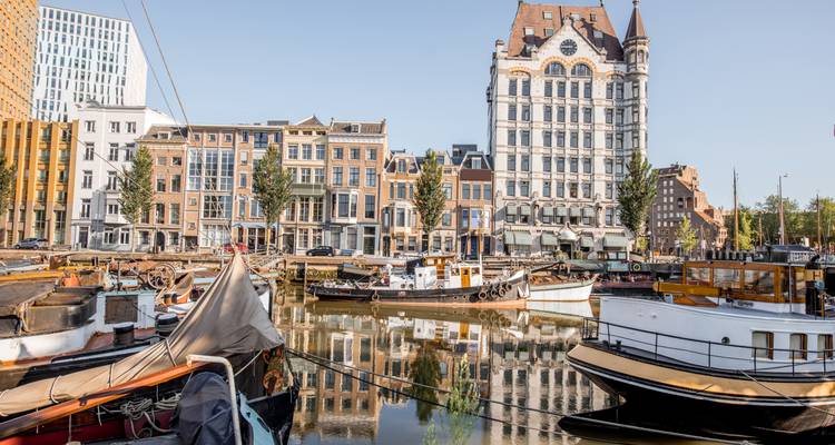 Puerto histórico con barcos tradicionales y edificio alto al fondo.