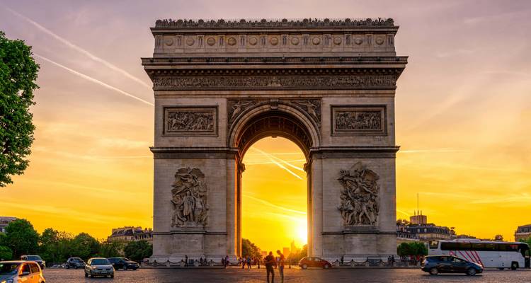 Vista del atardecer del Arco del Triunfo con gente en la calle.