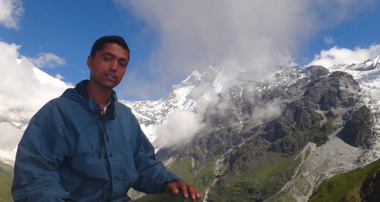Homme sur une montagne avec des sommets enneigés en arrière-plan.