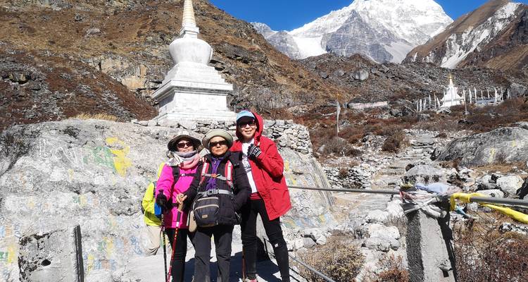 Groupe de personnes posant devant un paysage montagneux avec un stupa.