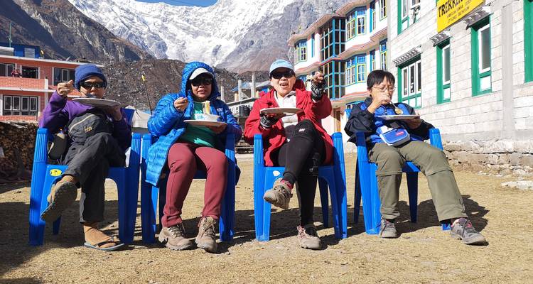 Quatre personnes assises en train de manger dans un cadre extérieur avec des montagnes.