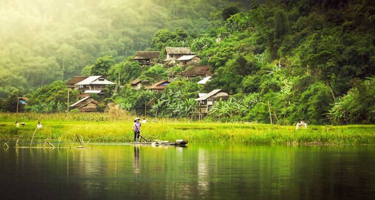 Un lago sereno con casas tradicionales y vegetación exuberante.