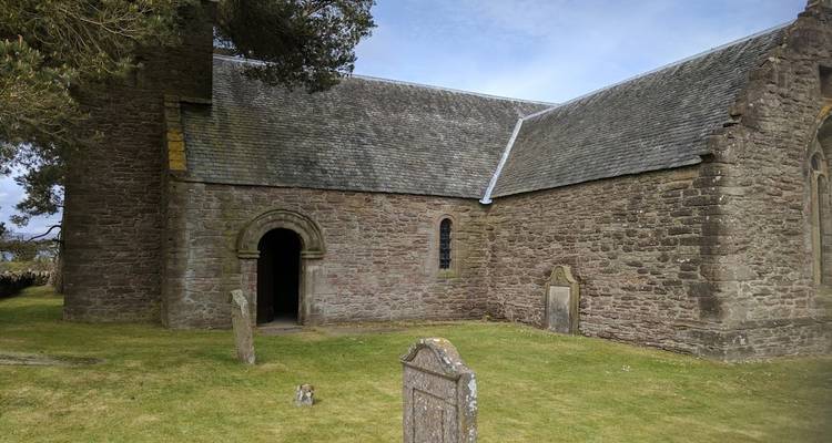 Old stone church with surrounding grave markers.