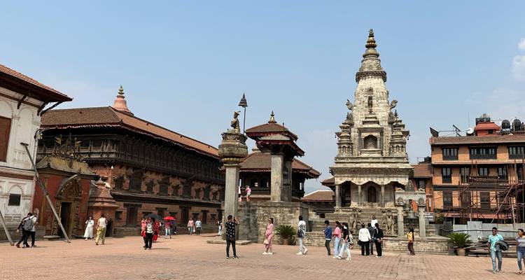 Kathmandu Durbar Square with people, old buildings, and dramatic architecture under a clear blue sky.