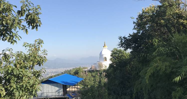 White stupa on a hill with valley and mountain view.