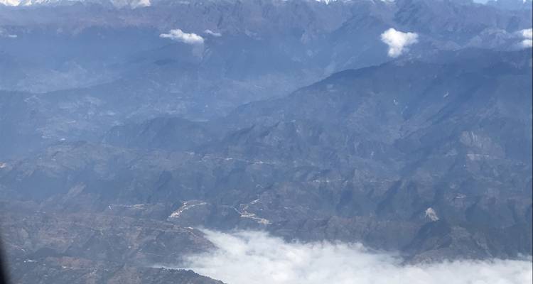 Aerial view of mountains and clouds from an airplane window.