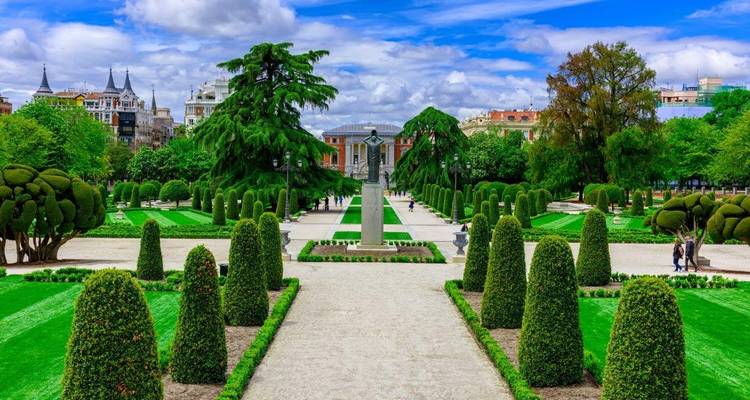 Well-manicured garden with statues and paths, flanked by neatly trimmed trees.