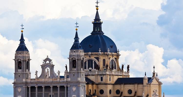 Close-up of a historic cathedral with domes and spires against a cloudy sky.