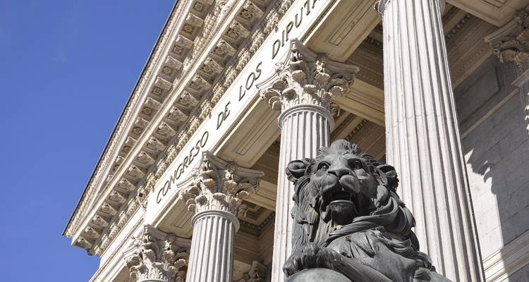 Close-up of columns and a sculpture outside a neoclassical building.