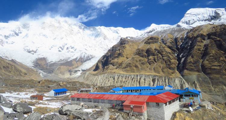 Chalets de montagne dans une vallée entourée de sommets enneigés.