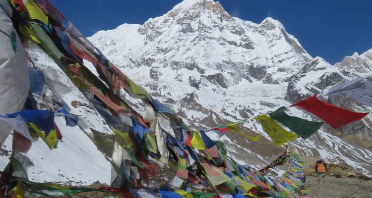 Colorful prayer flags with snowy peaks in the background.