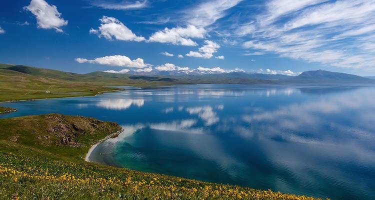 Scenic view of a lake with surrounding mountains and clear blue sky.