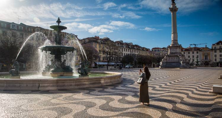 Mujer admirando la fuente de Rossio con el pavimento de mosaico brillando bajo el sol