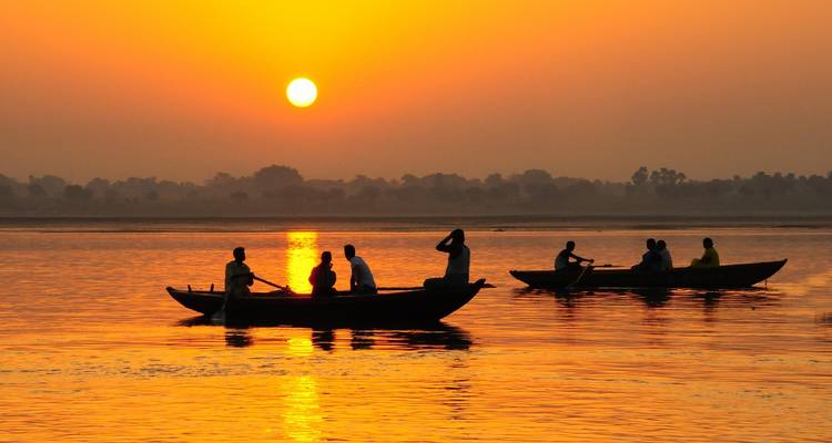 Boats on a river during a vibrant sunset.