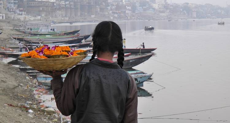 Femme portant un panier de fleurs le long d'une rive.