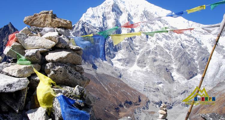 Vue de montagne avec des drapeaux de prière colorés au premier plan.