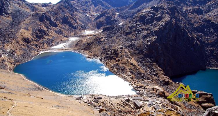Vue aérienne d'un lac de montagne bleu entouré d'un terrain rocheux.