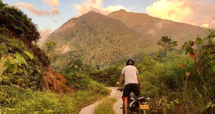 Person biking on a mountain trail during sunset.
