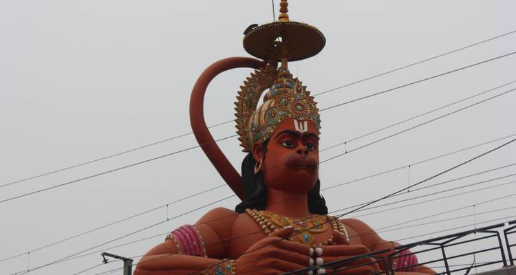 Large statue of a deity with cloudy sky background.