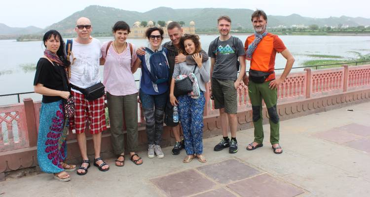 Group of people posing by a lake with hills in the background.