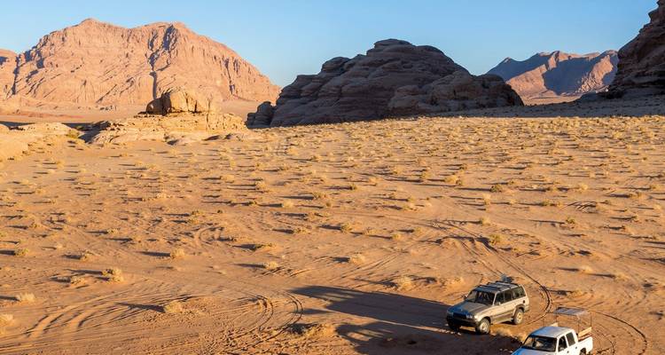 Woestijnlandschap met 4x4 voertuigen nabij rotsformaties.