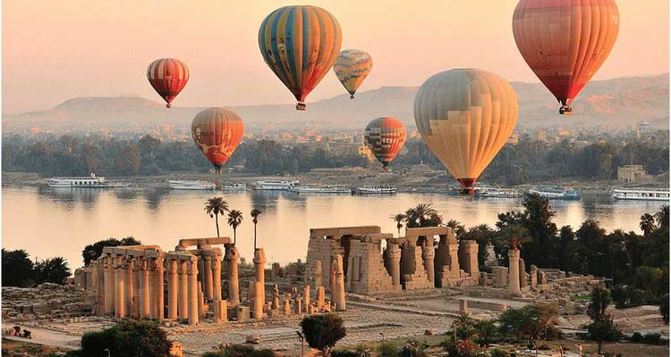 Globos de aire caliente sobre ruinas antiguas junto a un río.