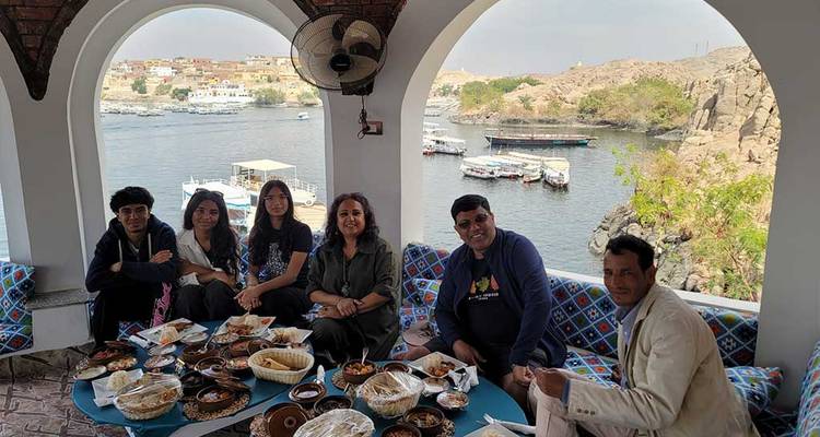 Cena grupal con vista al río Nilo y barcos.