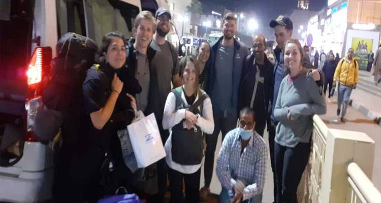 Grupo de turistas posando de noche cerca de una furgoneta.
