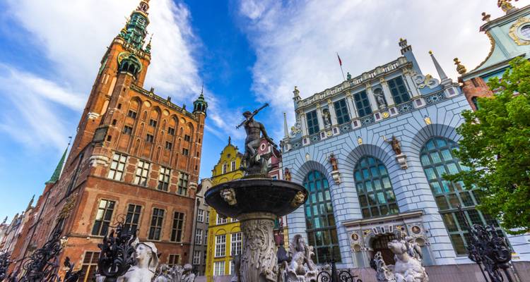 Fontaine de Neptune avec des bâtiments historiques ornés sur le Long Marché de Gdansk sous un ciel bleu vif.